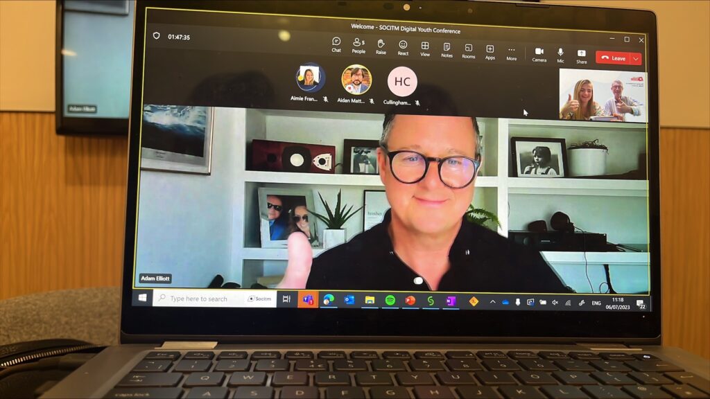 Adam Elliot on a laptop screen at the Youth Conference. The images shows other team members on the conference call on teams.