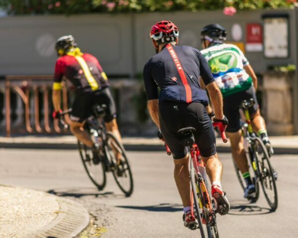 An image of 3 men on racing bikes riding on a street as part of a race. They were wearing lycra and helmets.