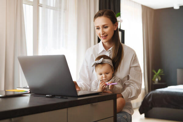 Young woman taking care of child at home and working remotely as digital company employee. Freelance distant work for specialists and professionals with children. Online solutions and programs for fun