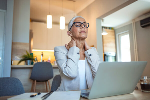 Cropped shot of a mature businesswoman looking stressed out while working in her office at home. Mature businesswoman having neck pain. Stressed mature woman massaging her neck.